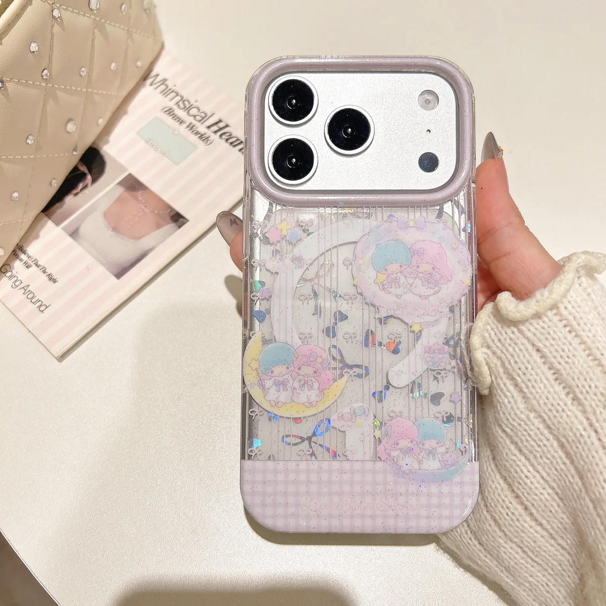 Clear pastel phone case with Little Twin Stars art, glitter details, a heart grip, and beaded strap