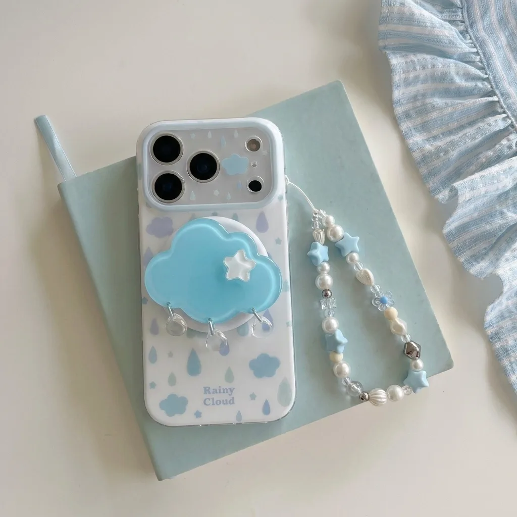 Clear phone case with rainy cloud print, blue cloud grip, and beaded strap on a pastel backdrop