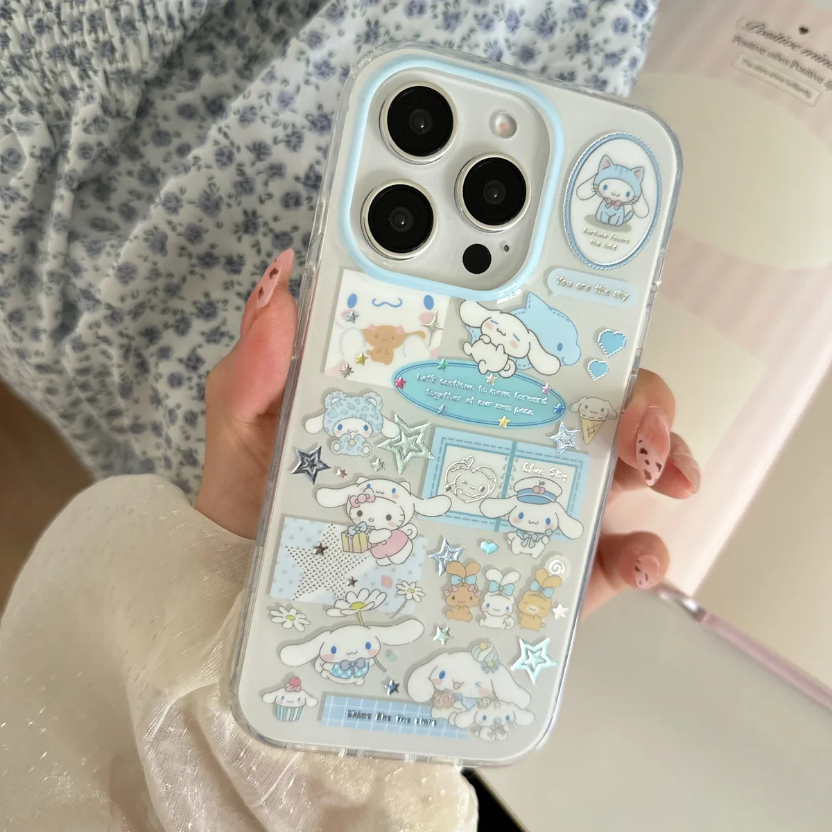 Clear iPhone case with Cinnamoroll stickers and a beaded strap, held in hand