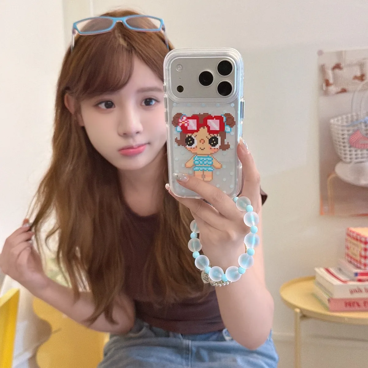 Clear phone case with a pixel girl graphic and a blue beaded wrist strap