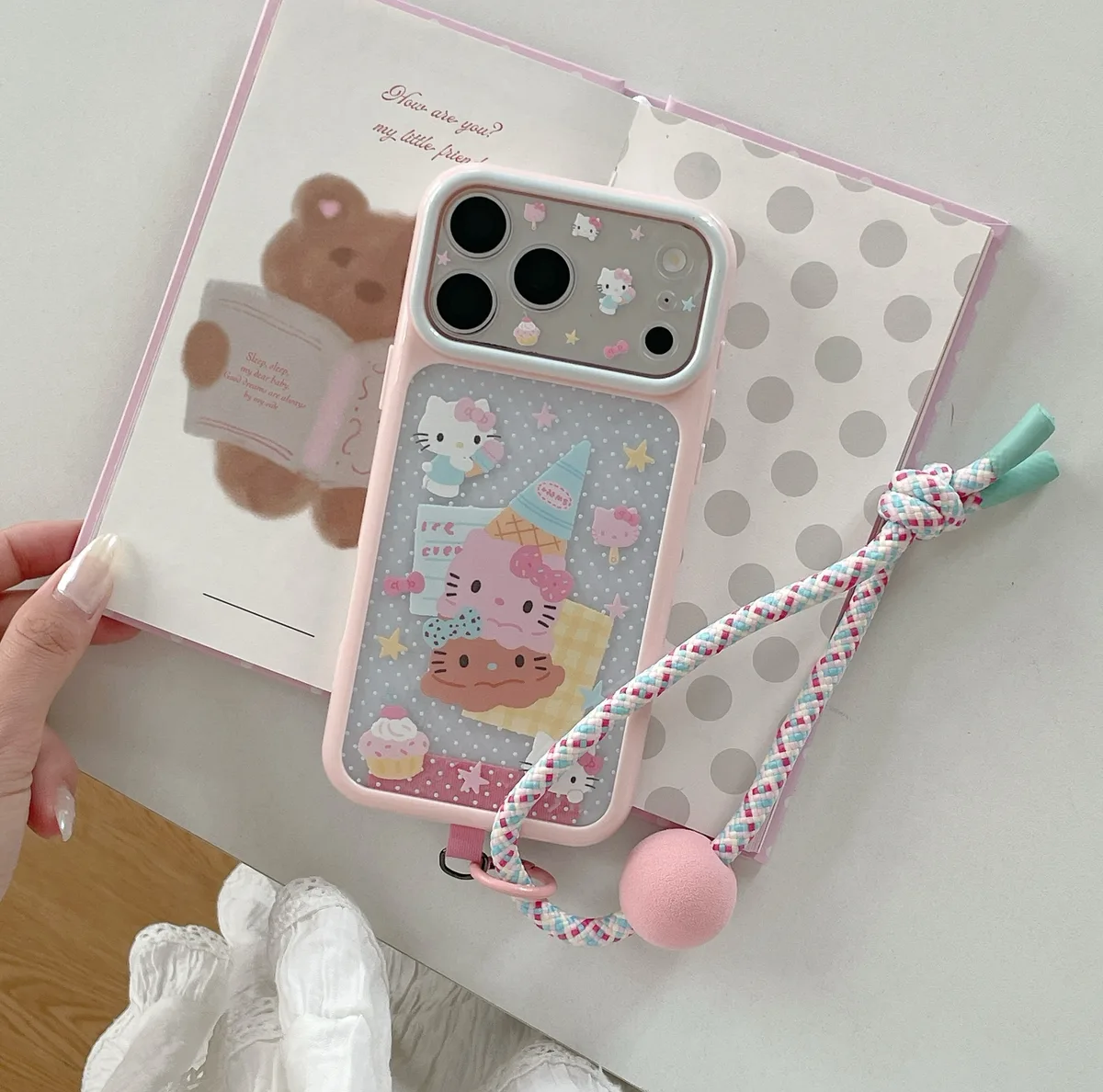 Pink Hello Kitty phone case with ice cream artwork and a braided wrist strap