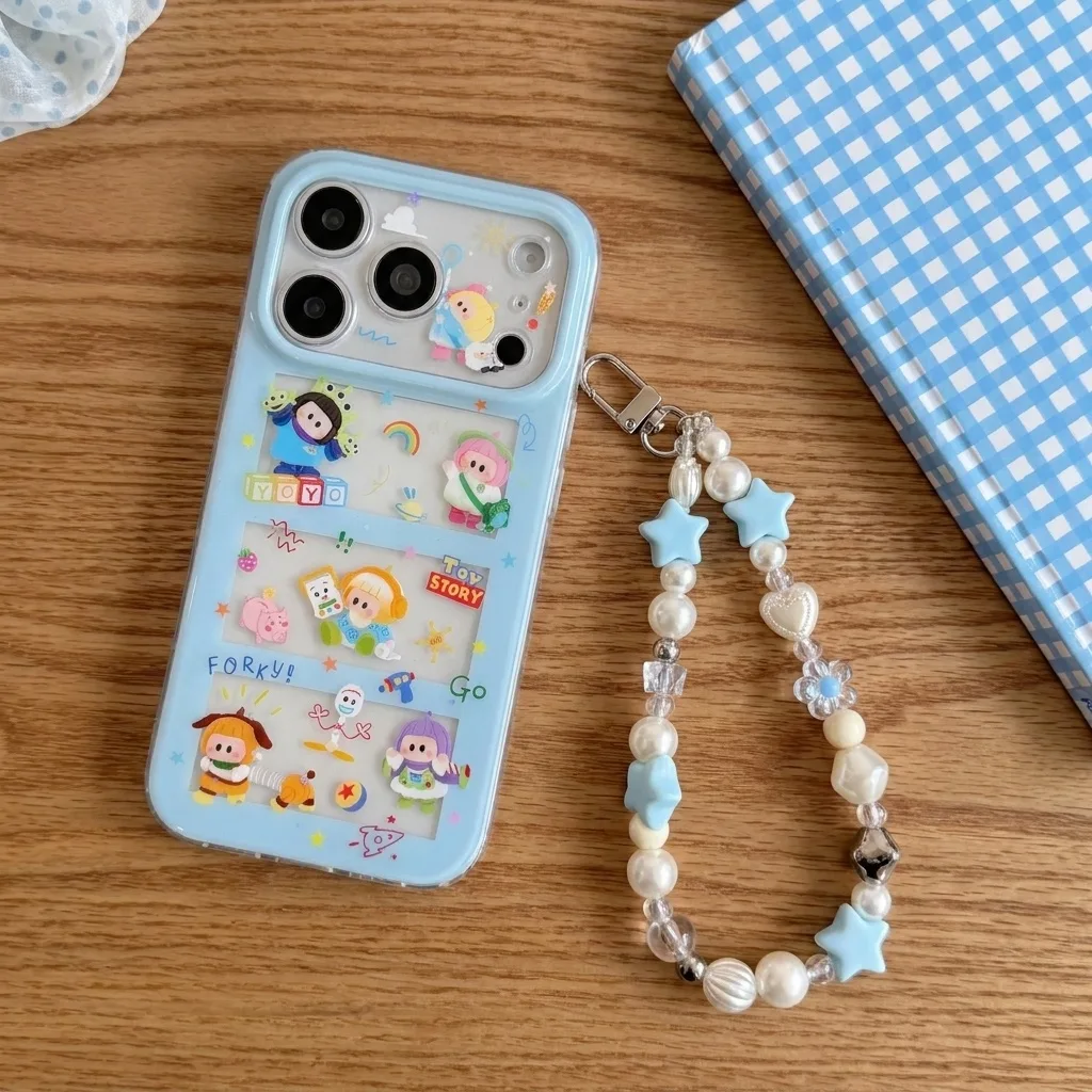 Light blue iPhone case with Toy Story characters and a beaded strap, held in hand on a wooden surface.